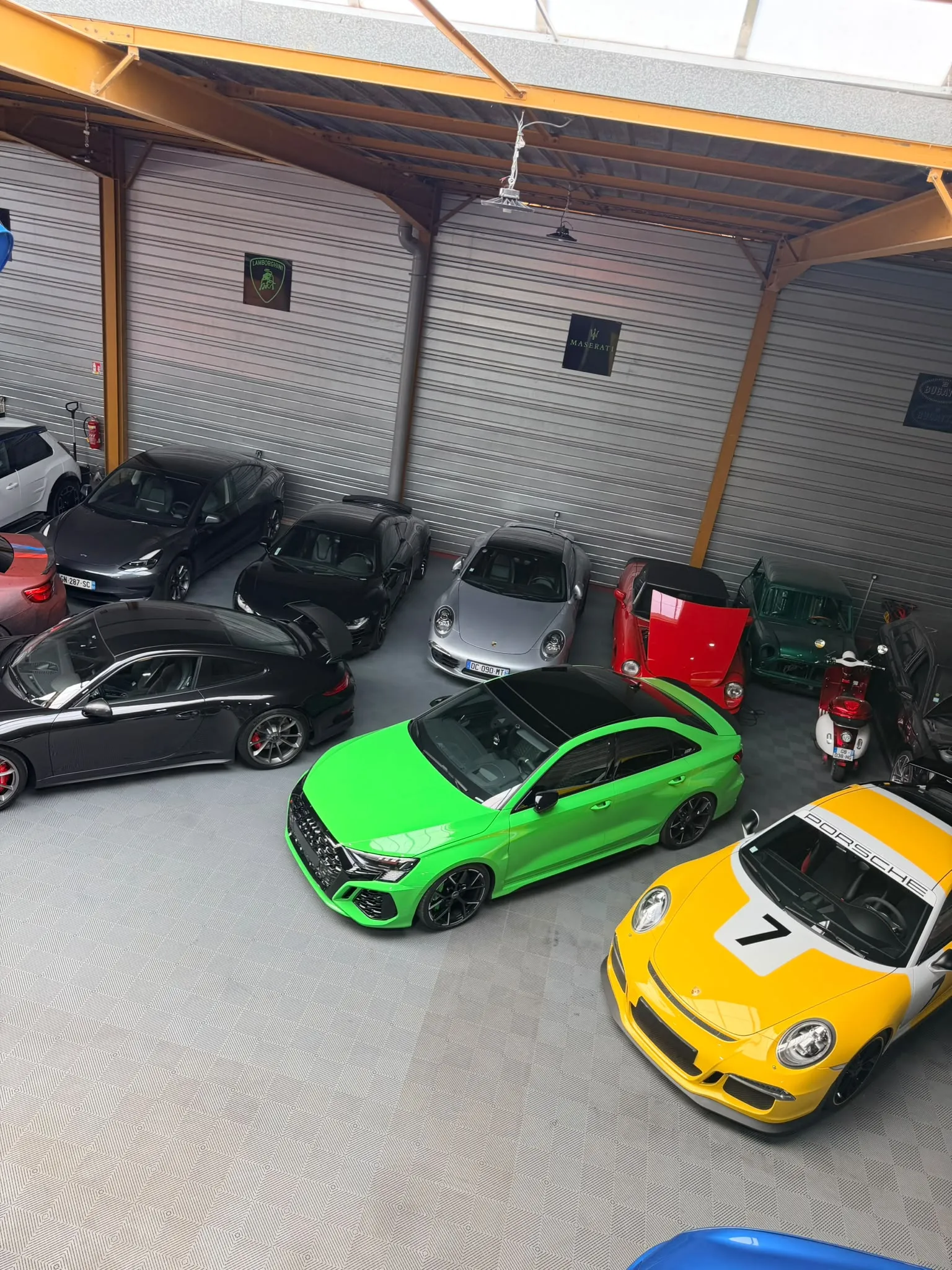 Audi RS3, Porsche 911 GT3 et Ferrari dans l’atelier, vue de la mezzanine
