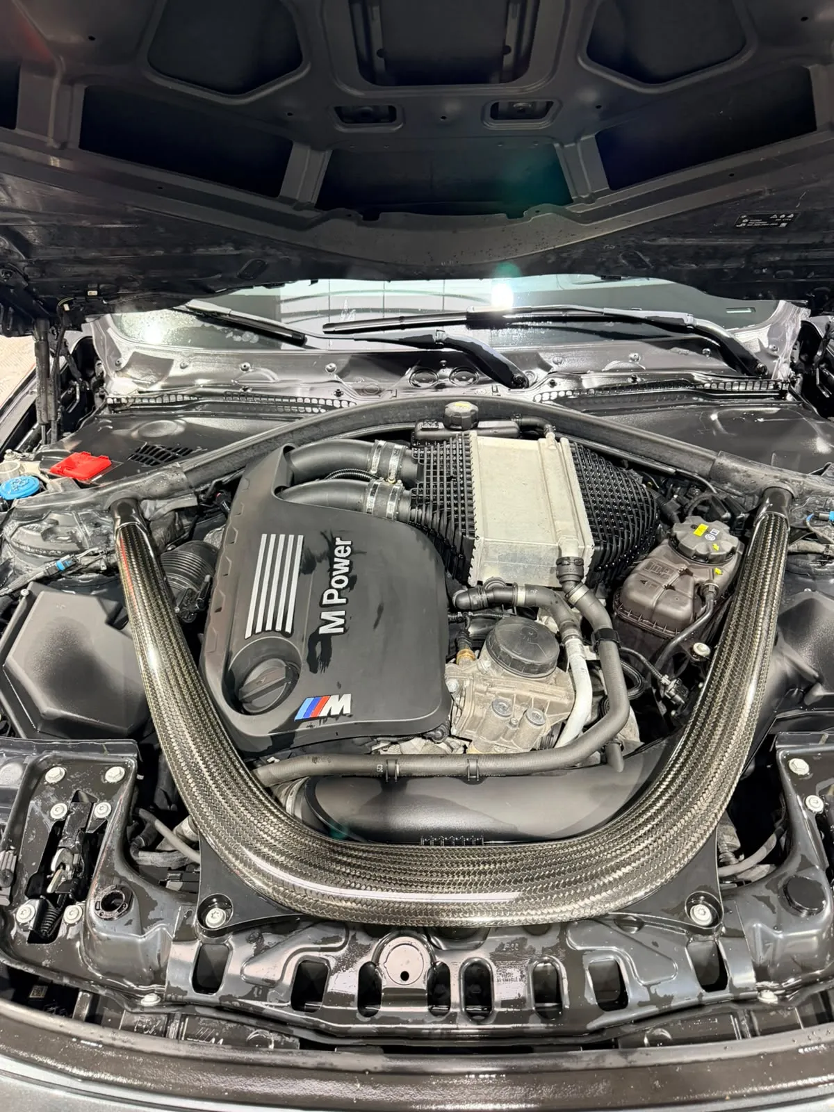 Moteur BMW M Power avec admission carbone, capot ouvert à l’atelier