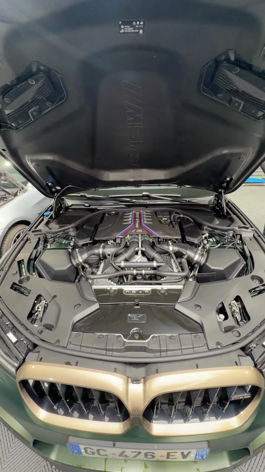Moteur BMW M5 sous le capot, calandre bronze, à l’atelier